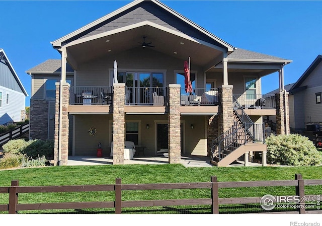 view of front facade with a patio, a balcony, ceiling fan, and a front lawn