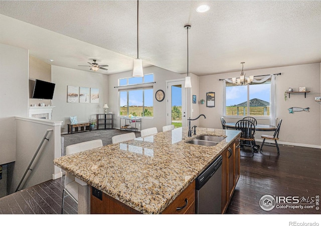 kitchen featuring sink, a kitchen island with sink, a wealth of natural light, decorative light fixtures, and stainless steel dishwasher