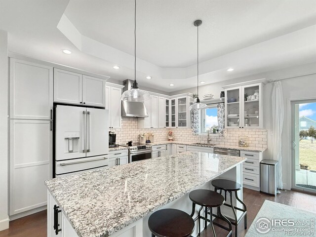 kitchen with high end fridge, stainless steel electric range, a center island, and white cabinets