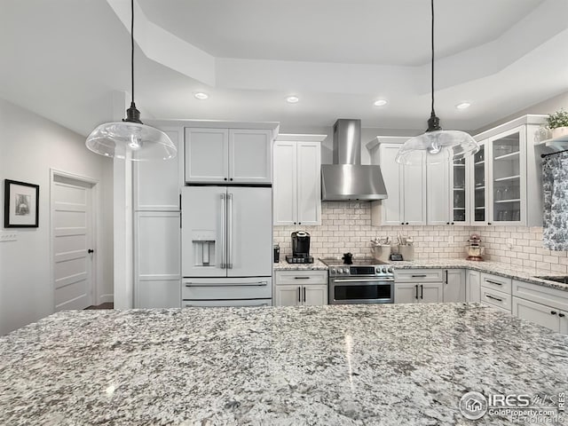 kitchen featuring high end fridge, white cabinetry, stainless steel electric range, pendant lighting, and wall chimney range hood