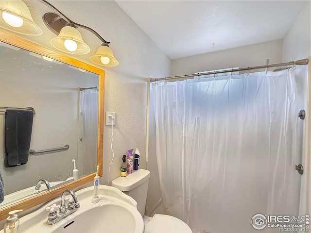 bathroom featuring sink, curtained shower, and toilet