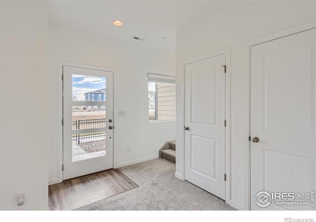 doorway to outside featuring light carpet