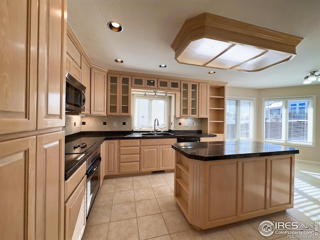 kitchen featuring light tile patterned flooring, appliances with stainless steel finishes, sink, a center island, and light brown cabinets