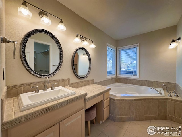 bathroom with tile patterned flooring, vanity, and tiled tub