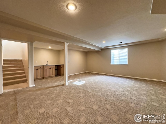 basement with light colored carpet, sink, and a textured ceiling