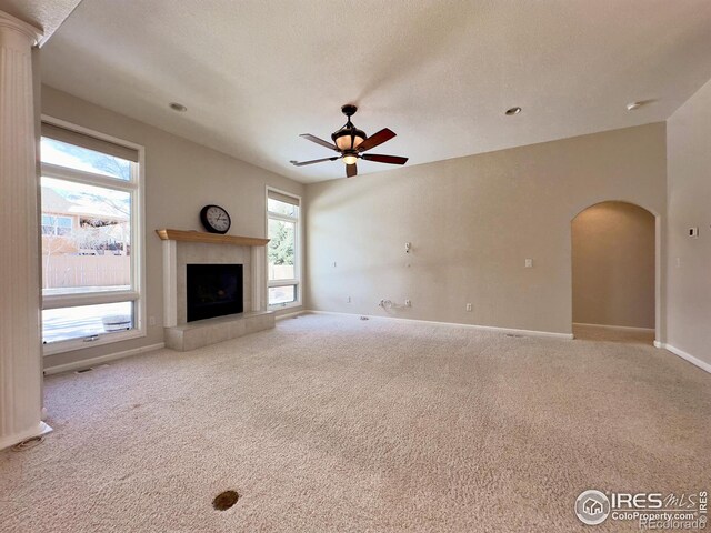 unfurnished living room featuring ceiling fan, a fireplace, light carpet, and a textured ceiling