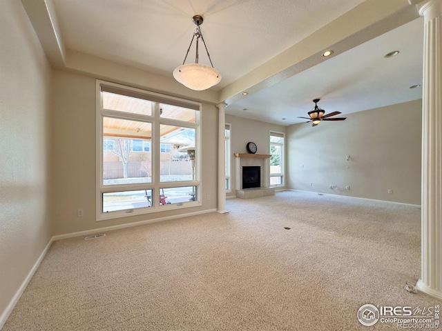 unfurnished living room featuring ceiling fan, decorative columns, and carpet