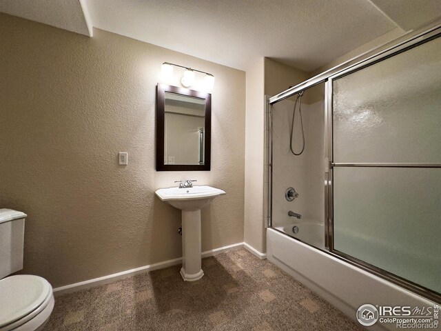 bathroom with toilet and shower / bath combination with glass door