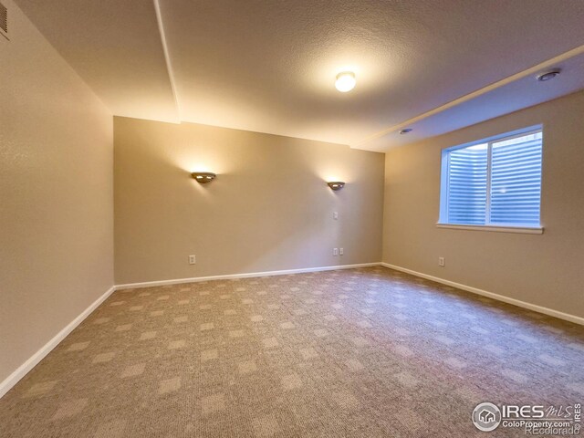 carpeted empty room with a textured ceiling