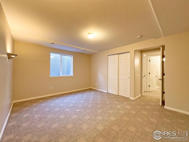 unfurnished bedroom featuring light carpet and a closet