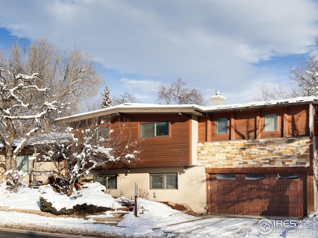 snow covered property with a garage