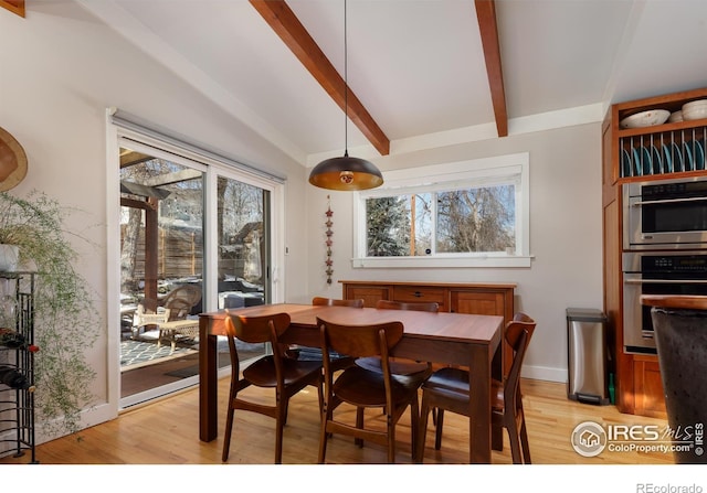 dining room featuring lofted ceiling with beams and light hardwood / wood-style flooring