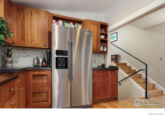 kitchen with high end fridge, decorative backsplash, and light wood-type flooring