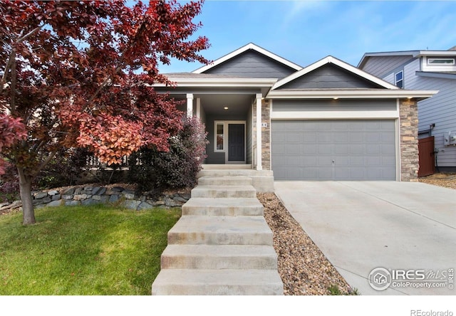 1484 First Light Dr, Windsor, CO 80550 - view of front facade featuring a garage, driveway, stone siding, and a front lawn