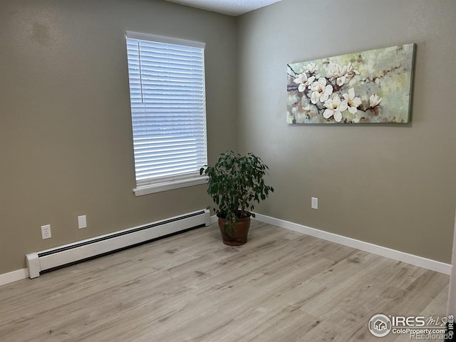 unfurnished room with baseboard heating and light hardwood / wood-style flooring