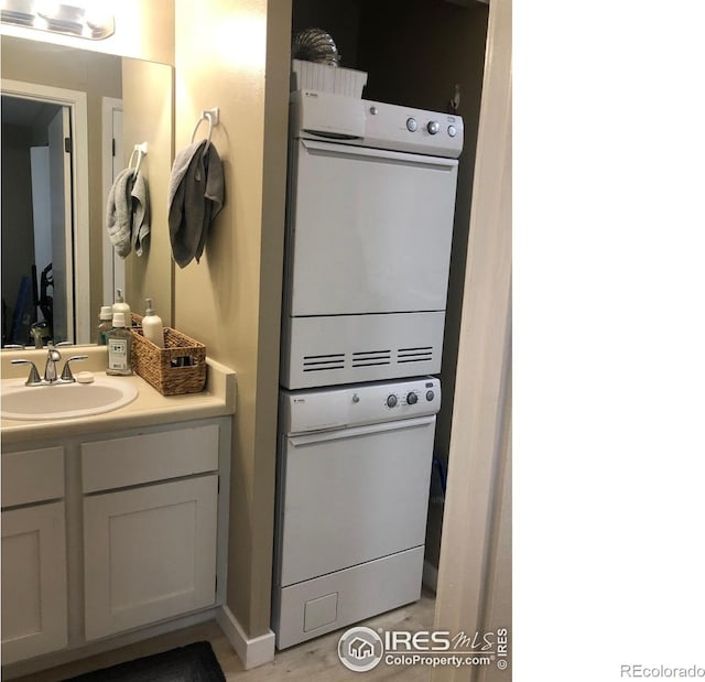 bathroom with stacked washing maching and dryer and vanity