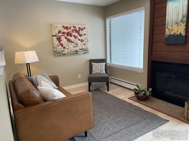 living room with a baseboard radiator, wood-type flooring, and a large fireplace