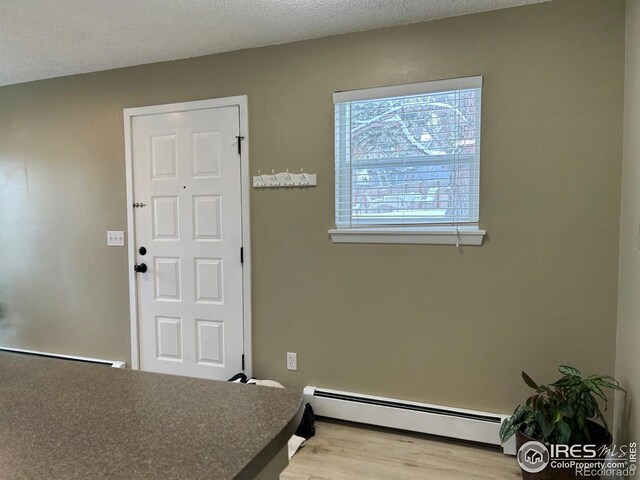 entryway featuring hardwood / wood-style floors, a textured ceiling, and a baseboard heating unit