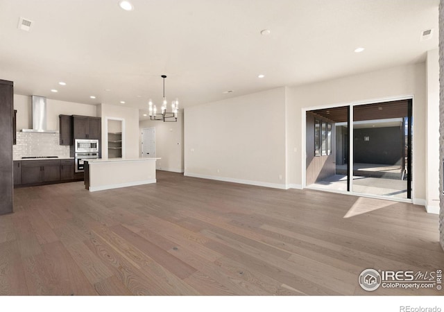 unfurnished living room featuring a chandelier and light wood-type flooring