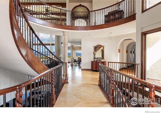 tiled entrance foyer featuring a towering ceiling and decorative columns