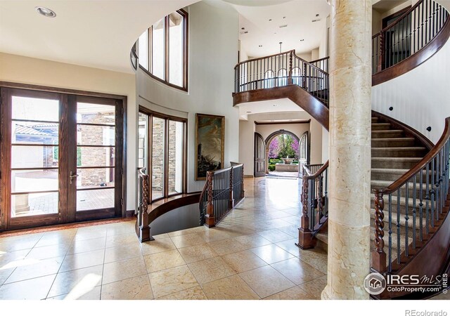 entrance foyer featuring french doors, a towering ceiling, and plenty of natural light