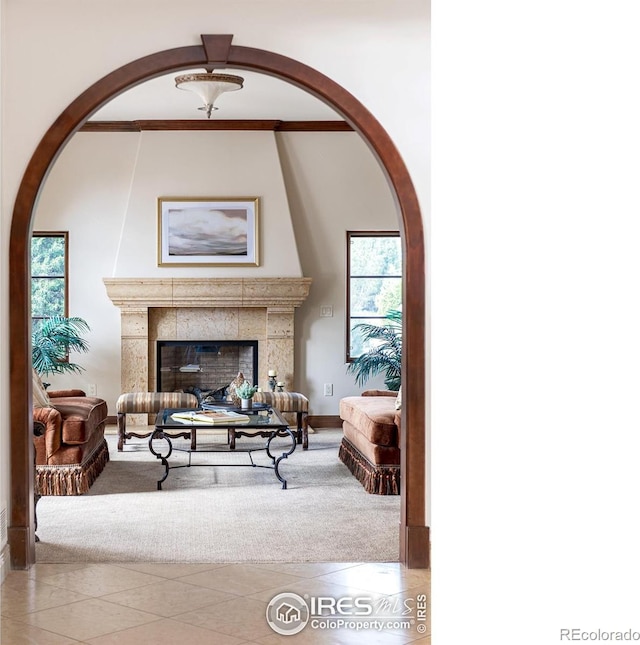 sitting room with a tiled fireplace, light tile patterned floors, and a healthy amount of sunlight