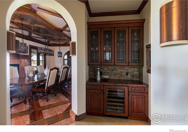 bar featuring wine cooler, backsplash, dark stone counters, hanging light fixtures, and ornamental molding