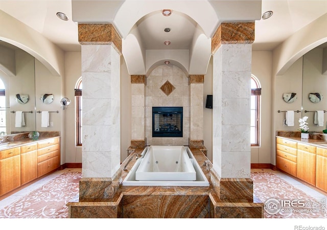 bathroom featuring vanity, a fireplace, and tiled bath