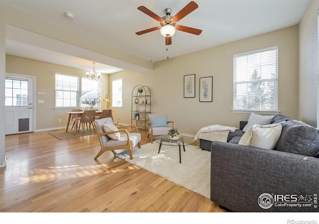 living room featuring hardwood / wood-style flooring, a healthy amount of sunlight, and ceiling fan with notable chandelier