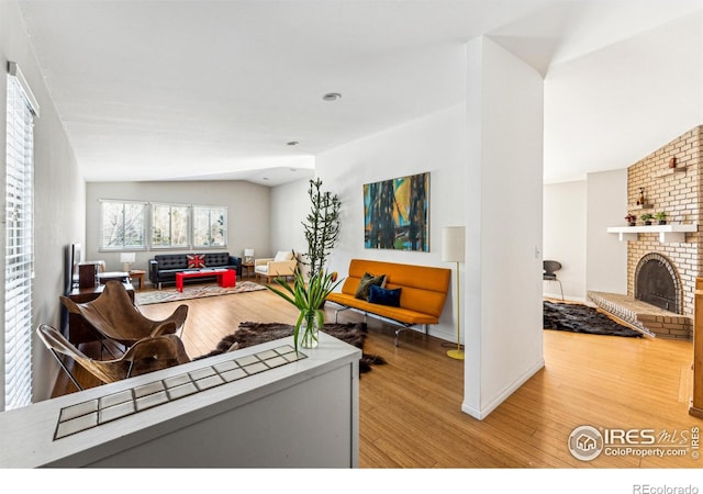 living room featuring a fireplace, wood-type flooring, and vaulted ceiling