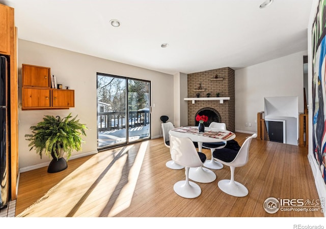 dining room with a brick fireplace, lofted ceiling, and light hardwood / wood-style floors