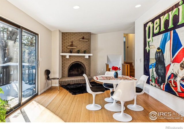 dining space with hardwood / wood-style flooring, a fireplace, and vaulted ceiling