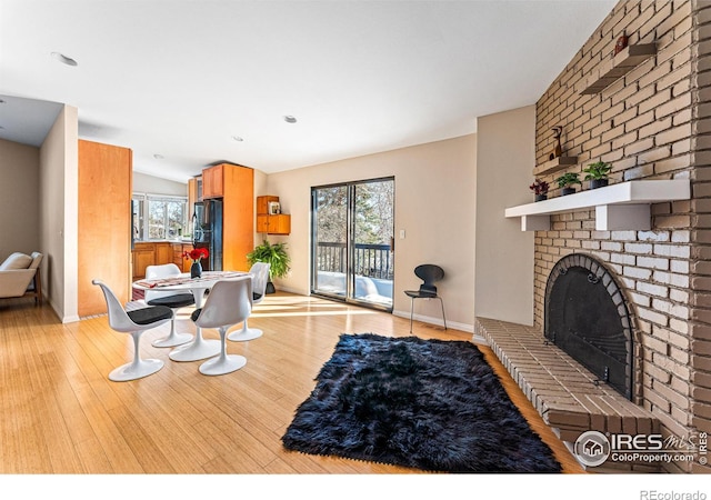 living room featuring lofted ceiling, a fireplace, and light hardwood / wood-style floors