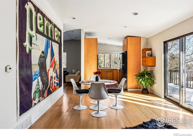 dining area with vaulted ceiling, wood-type flooring, and sink