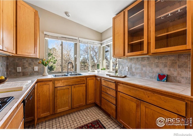 kitchen with light tile patterned flooring, stainless steel gas stovetop, lofted ceiling, sink, and tile counters