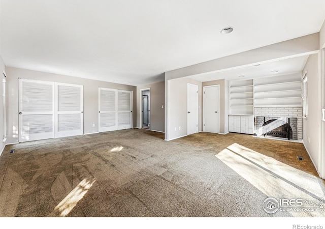 unfurnished living room with built in shelves, a fireplace, and carpet