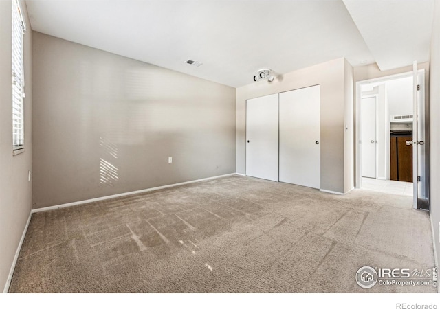 unfurnished bedroom featuring light colored carpet and a closet