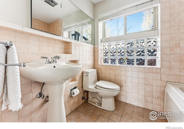 bathroom featuring tile walls, tile patterned floors, and toilet