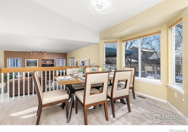 carpeted dining area with plenty of natural light and vaulted ceiling