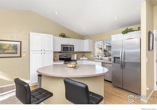 kitchen with a breakfast bar area, stainless steel appliances, and white cabinets