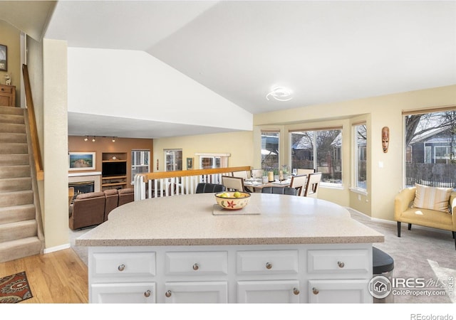 kitchen featuring white cabinetry, vaulted ceiling, and light hardwood / wood-style flooring