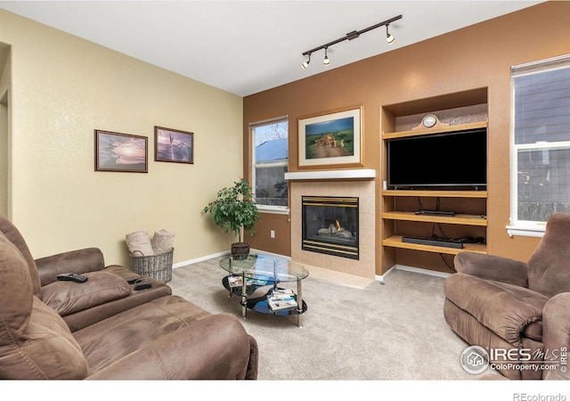 carpeted living room with a fireplace, built in features, and rail lighting