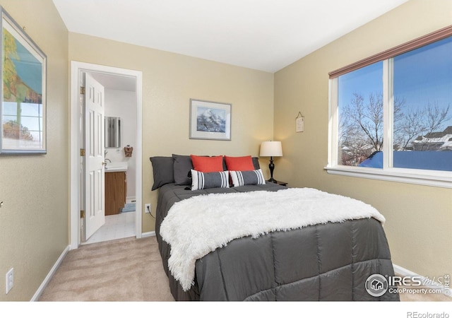 bedroom with ensuite bath and light carpet