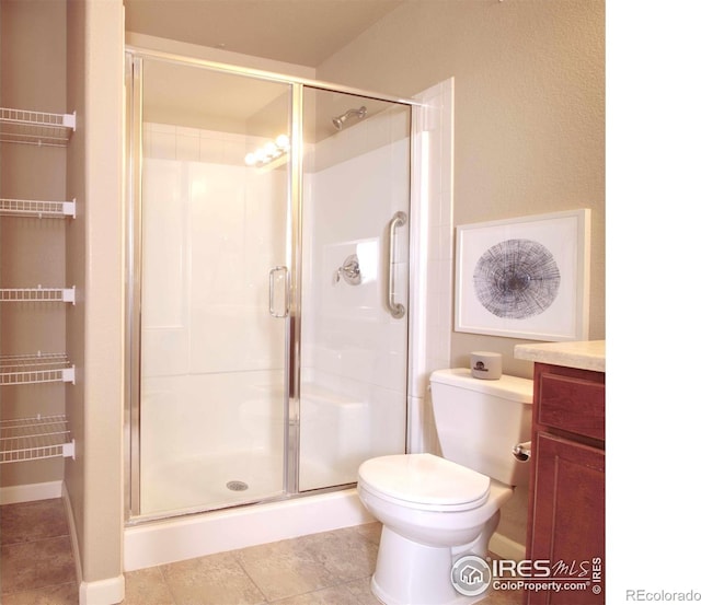 bathroom featuring vanity, a shower with shower door, and toilet