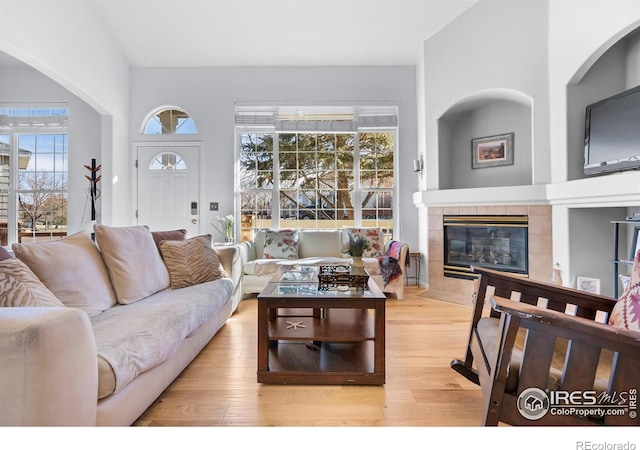 living room with a tile fireplace and light wood-type flooring