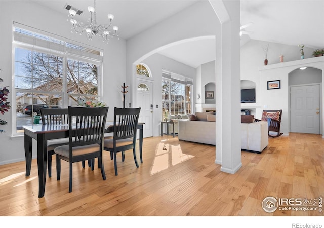 dining space with an inviting chandelier, high vaulted ceiling, and light hardwood / wood-style floors