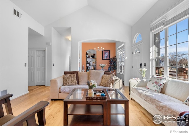 living room with high vaulted ceiling, a notable chandelier, and light wood-type flooring