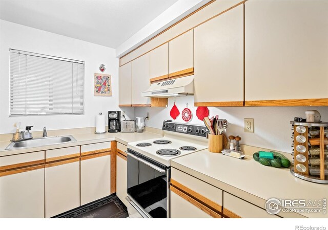 kitchen featuring white electric stove, sink, and white cabinets