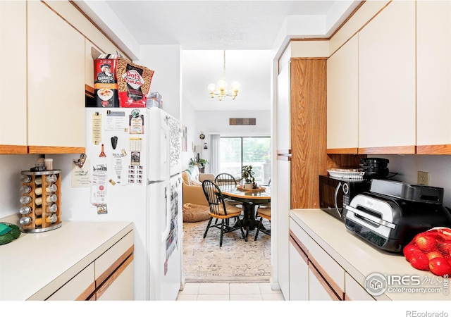 kitchen with white cabinetry, decorative light fixtures, a chandelier, light tile patterned floors, and white fridge