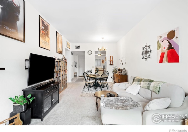 carpeted living room with an inviting chandelier